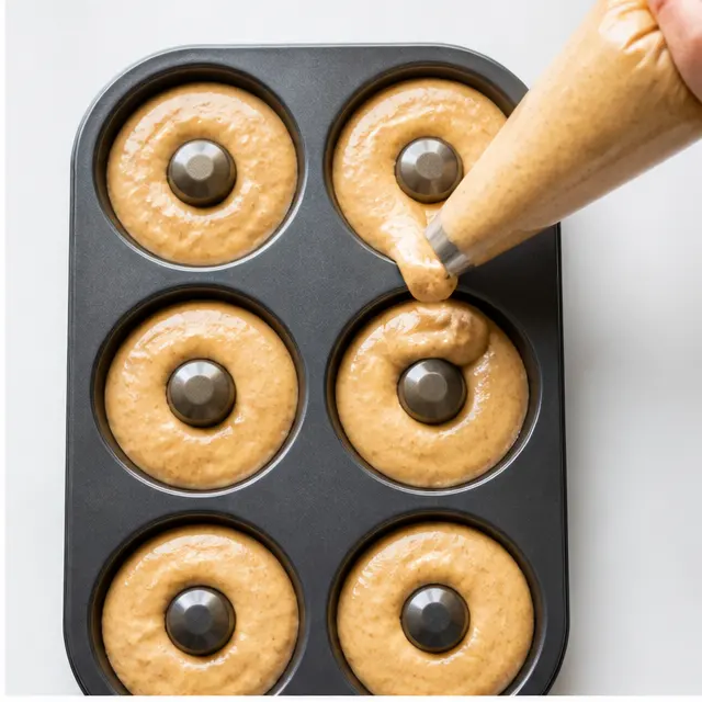 Piping thick batter into a greased donut pan