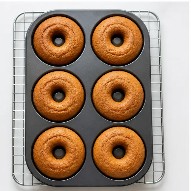 Baked golden donuts cooling on a wire rack