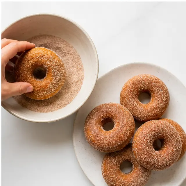 Tossing warm donuts in spiced sugar coating