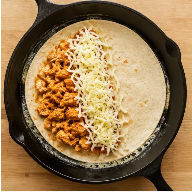 Step 2: Layering chicken and shredded cheese on the tortilla in the skillet