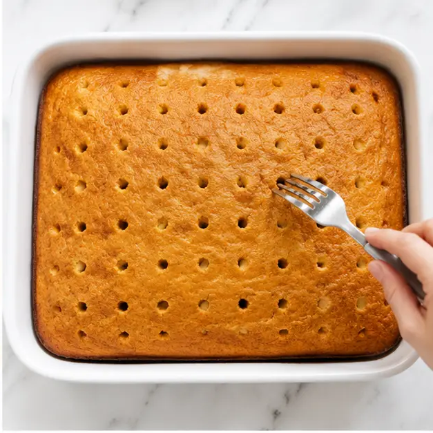 Step 2: Poking deep holes in the warm baked cake with a fork