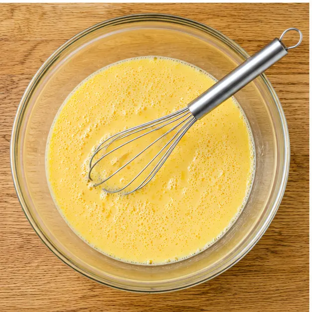 Step 3: Whisking large eggs and whole milk into a frothy seasoned custard