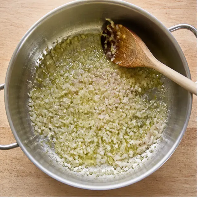 Sautéing minced shallot in olive oil until soft and fragrant