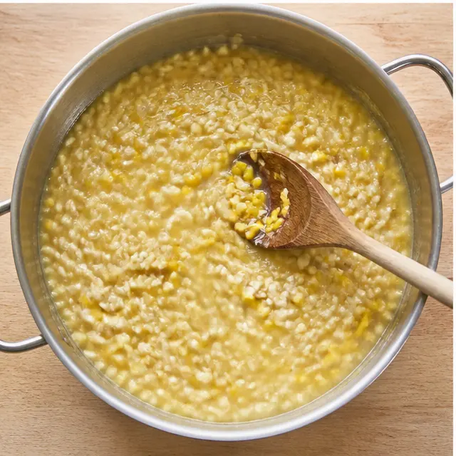 Stirring fresh corn kernels into the simmering risotto with warm broth
