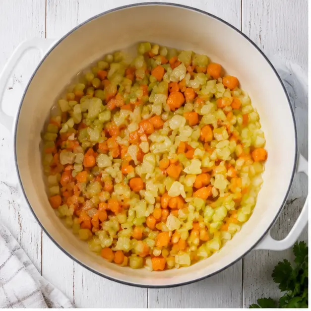 Sauteing diced onion, carrots, and celery in olive oil in a heavy Dutch oven