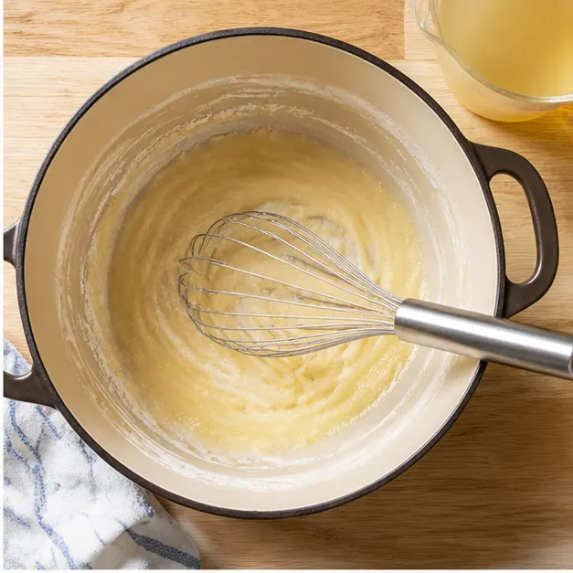 Whisking the roux into a smooth creamy sauce
